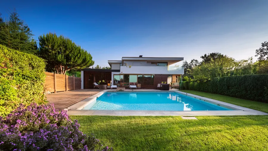 Gepflegter Garten mit Pool und Terrasse vor einem modernen Haus